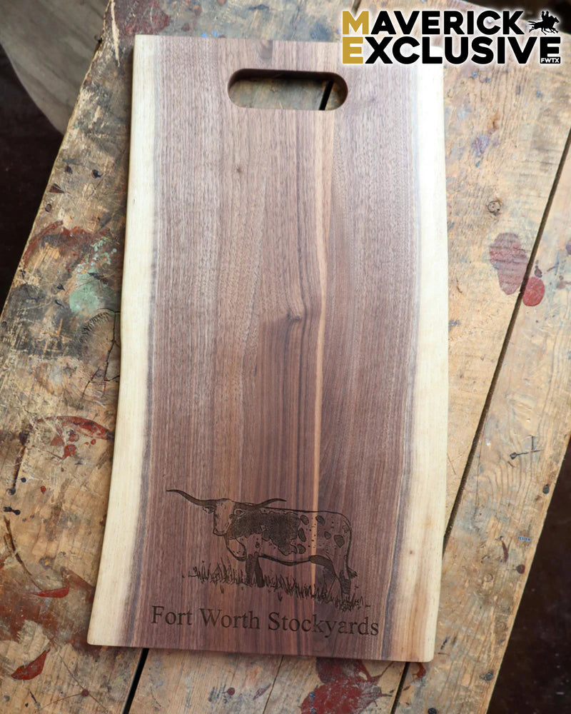 Wooden cutting board with engraved longhorn cow design and 'Fort Worth Stockyards' text on a rustic surface, branded 'Maverick Exclusive'.