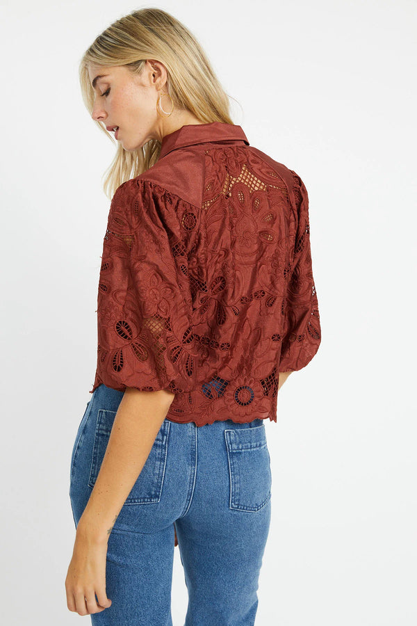 Woman wearing a red embroidered jacket and blue jeans on a white background