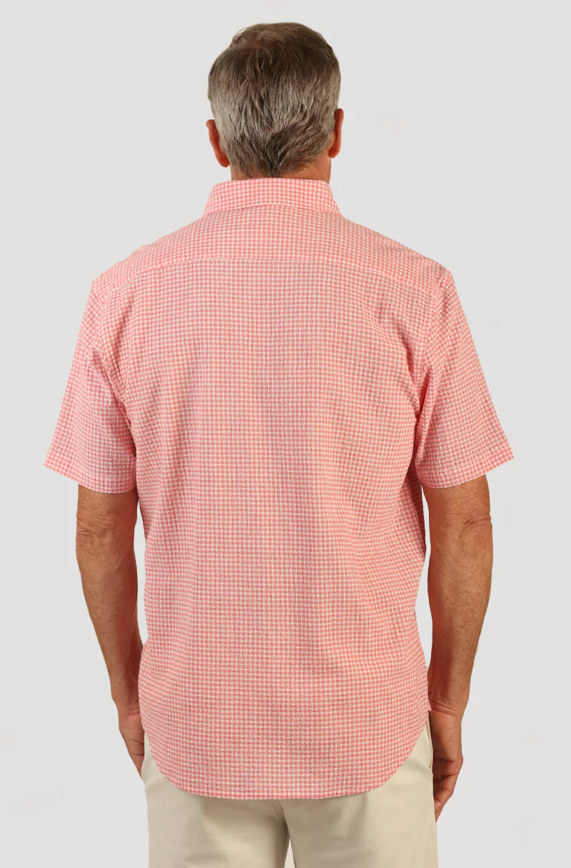 Man wearing short sleeve button front shirt with collar, pink and white checker print and single breast pocket