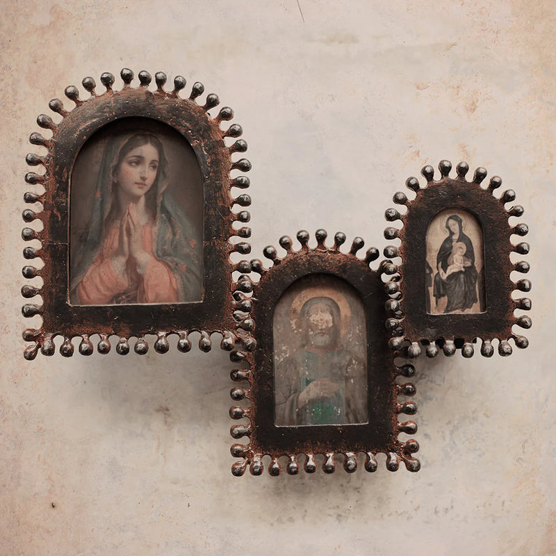 Three small religious portraits in ornate metal frames on a textured beige background