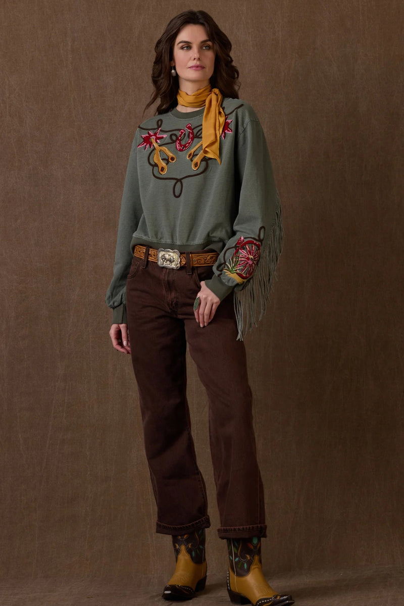 Person wearing a green sweater with embroidery, brown pants, and boots on a brown background with 'Double-D Ranch' branding.