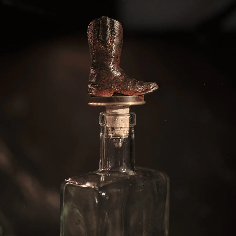 Decorative bottle stopper shaped like a cowboy boot on a dark background