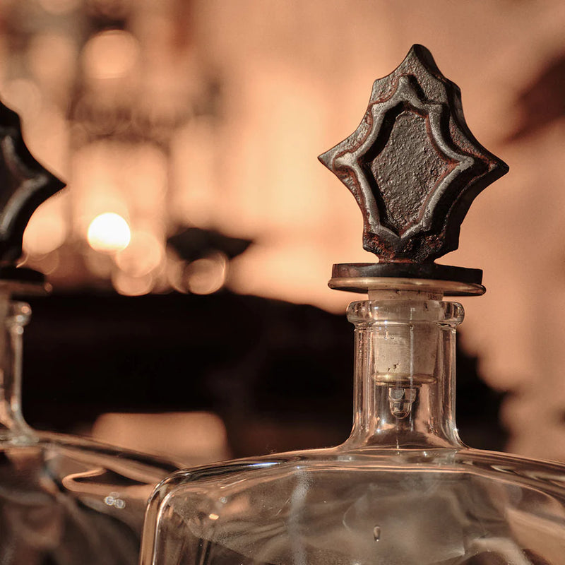 Close-up of a glass bottle with a decorative metal cap against a blurred background