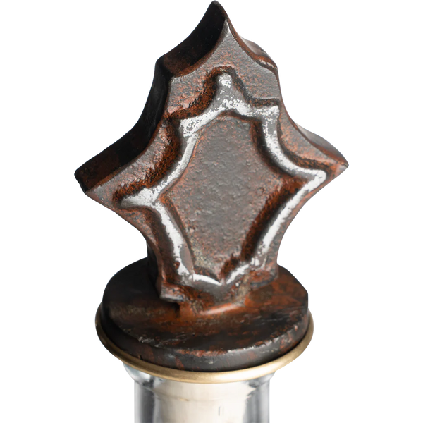 Decorative metal bottle stopper with star-shaped design on a white background