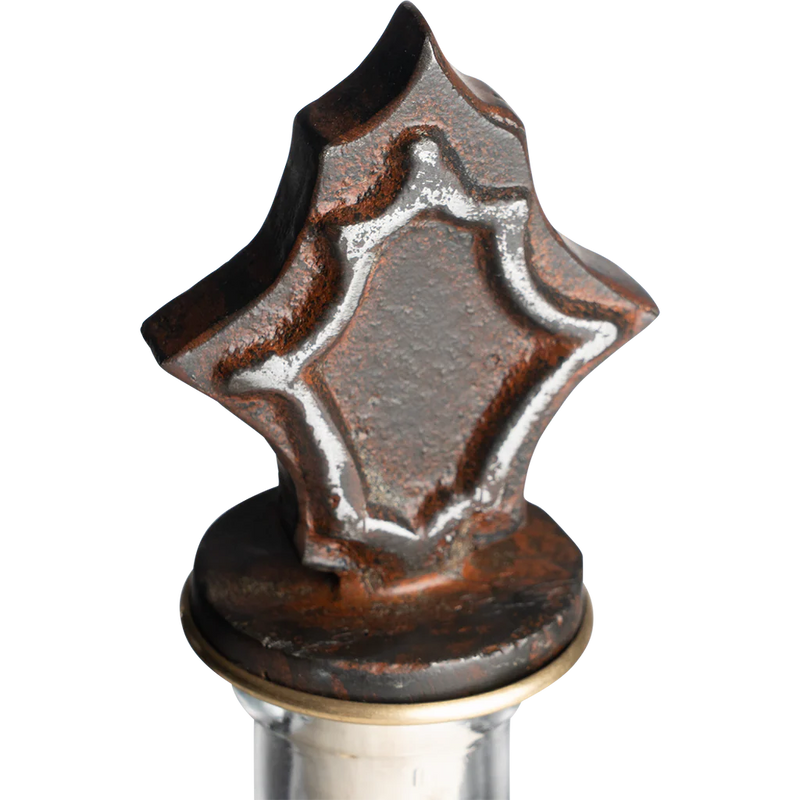 Decorative metal bottle stopper with star-shaped design on a white background