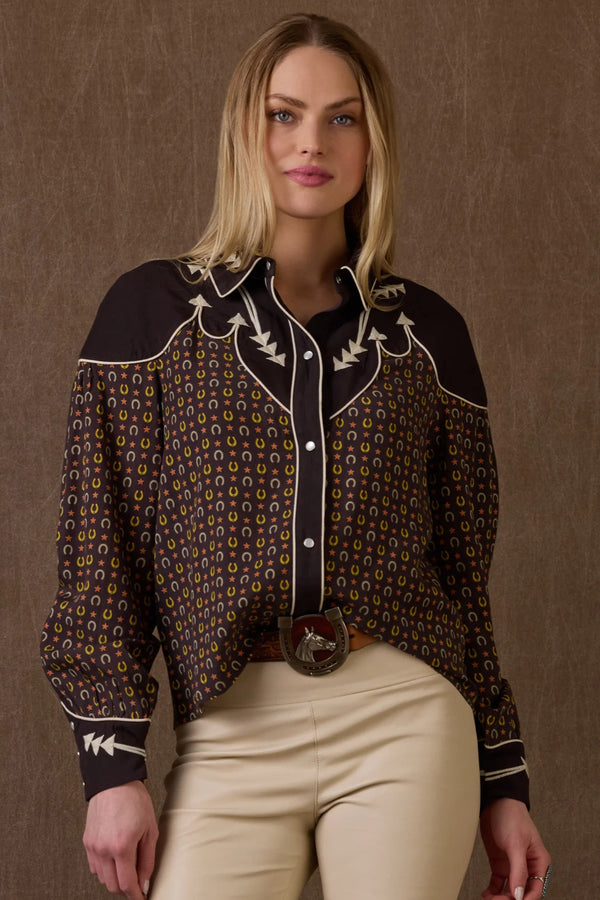 Woman wearing a patterned shirt with embroidered details on a brown background