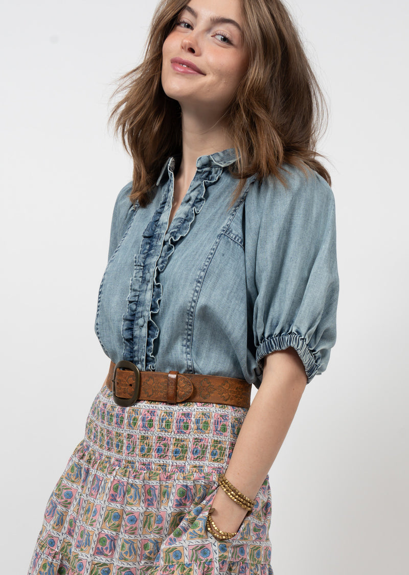 Woman wearing chambray shirt with ruffles down the front and puff sleeves