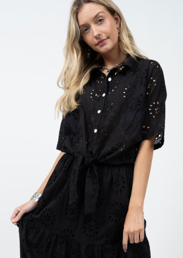 Woman wearing black button up short sleeve blouse with eyelet detail