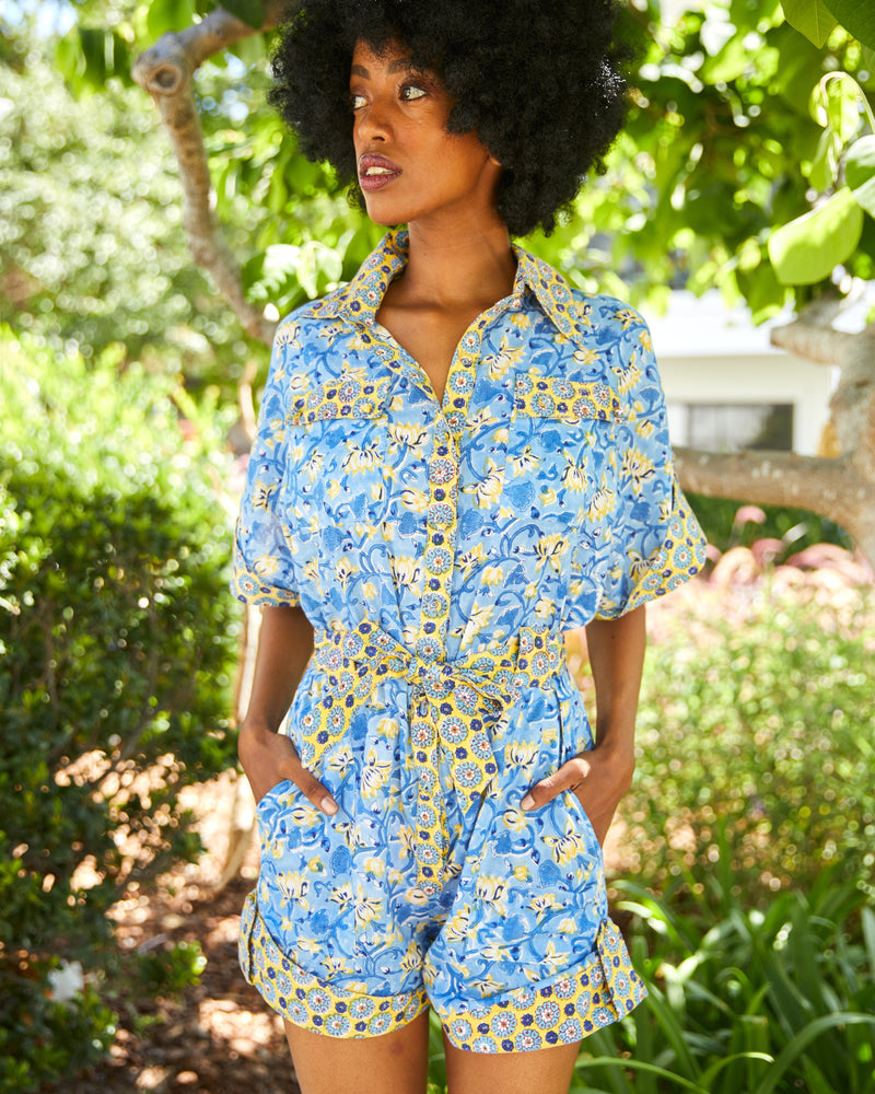 Woman wearing yellow and blue floral romper with matching belt