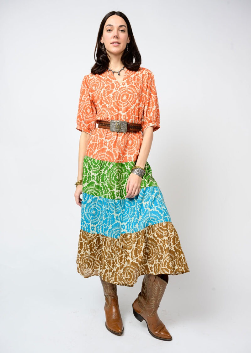 Woman wearing a colorful patterned dress with a belt and boots on a white background