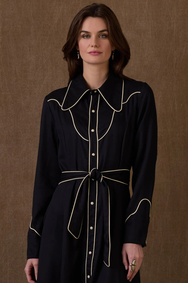 Woman wearing a black dress with white trim against a brown background, featuring the brand 'Double D Ranch'.