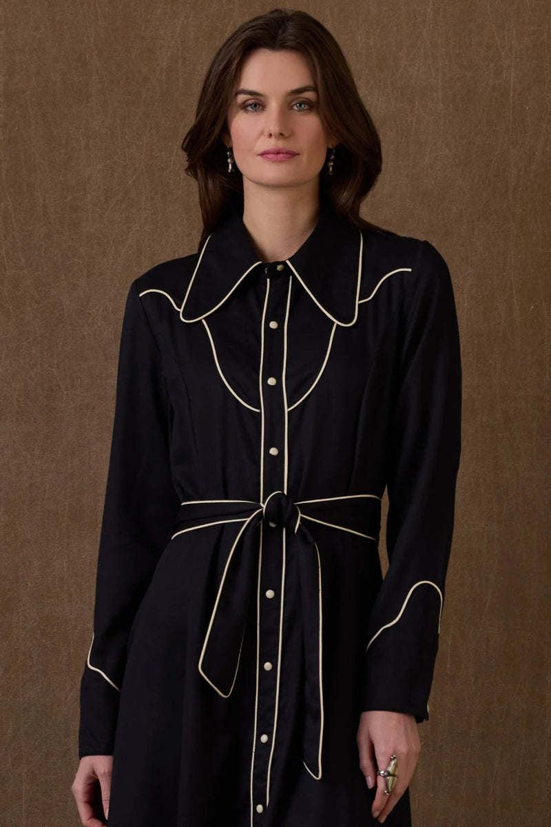 Woman wearing a black dress with white trim against a brown background, featuring the brand 'Double D Ranch'.