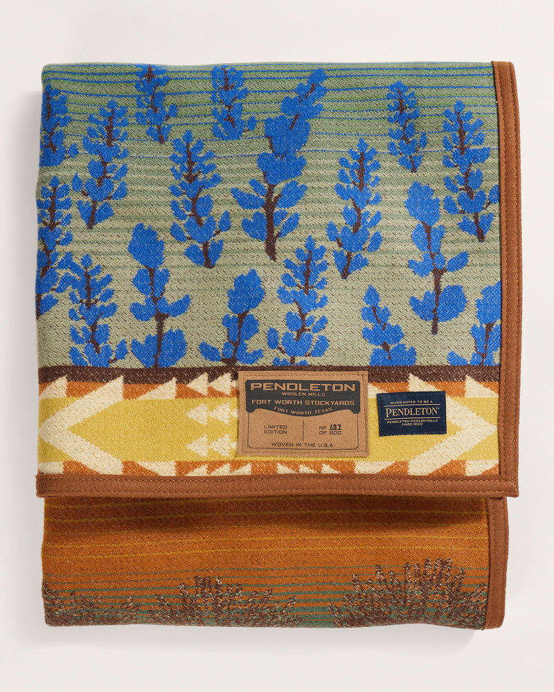Folded Pendleton blanket with blue tree pattern on a white background