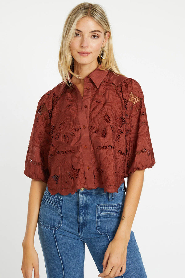 Woman wearing a red lace blouse and blue jeans on a white background