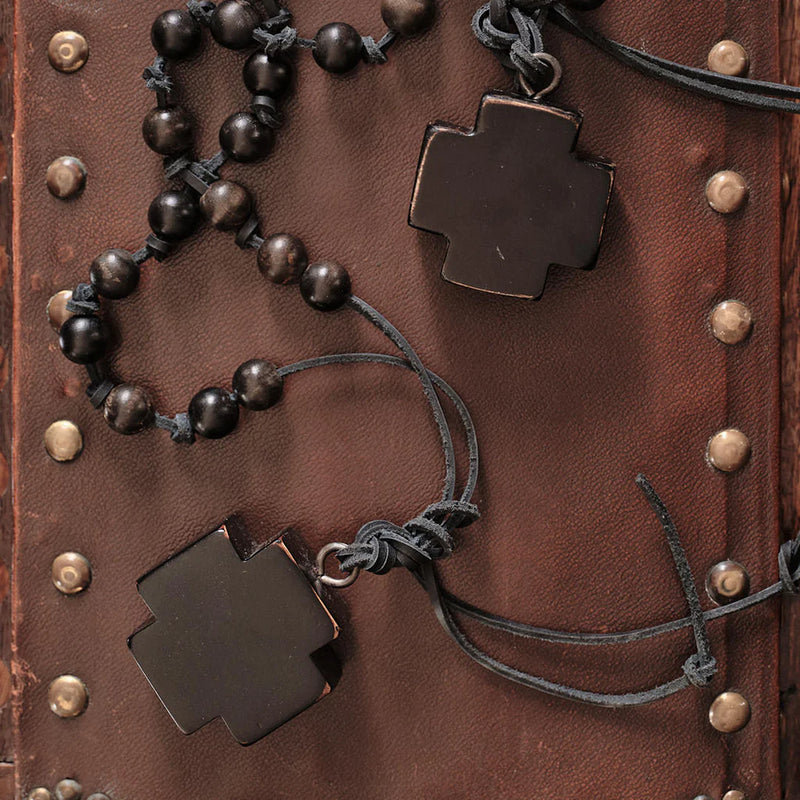 Bracelet with dark beads and cross-shaped charms on a brown leather background