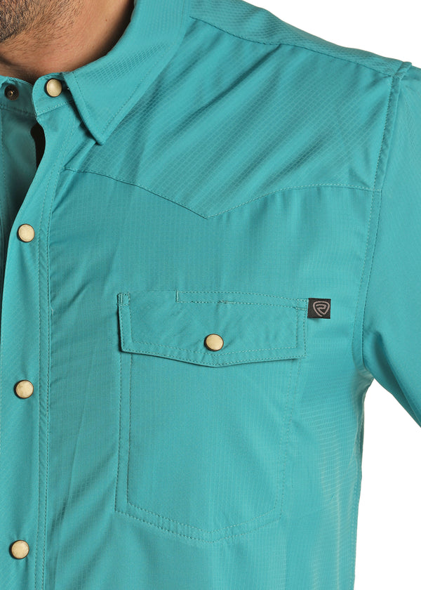 Man wearing pearl snap long sleeve shirt in a blue share with double button breast pockets