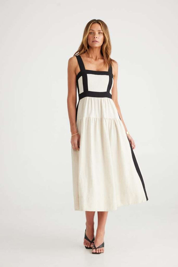 Woman wearing midi dress in cream with structured black lines contouring the upper portion of the dress