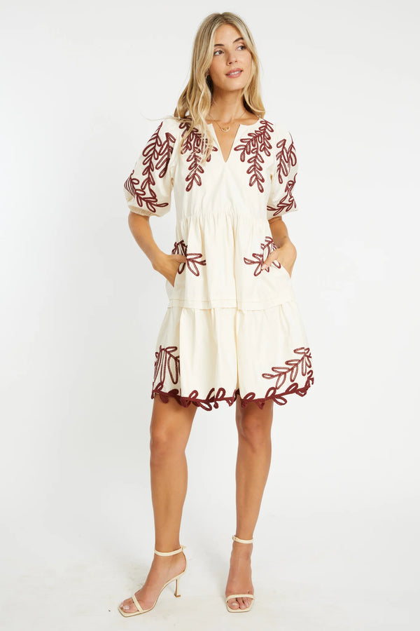 Woman wearing a white dress with red embroidery on a white background