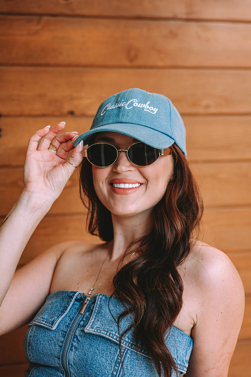 Woman wearing a denim cap and sunglasses against a wooden background
