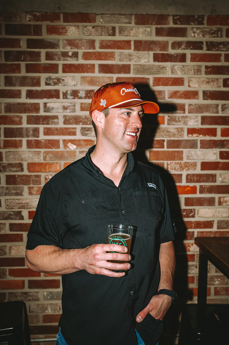 Man holding a beer mug against a brick wall