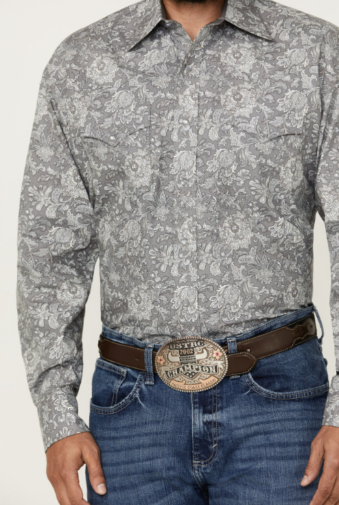 Man wearing long sleeve pearl snap shirt with paisley print all over, double breast pockets, and western yokes. This shirt is in a grey, white and blue color scheme 