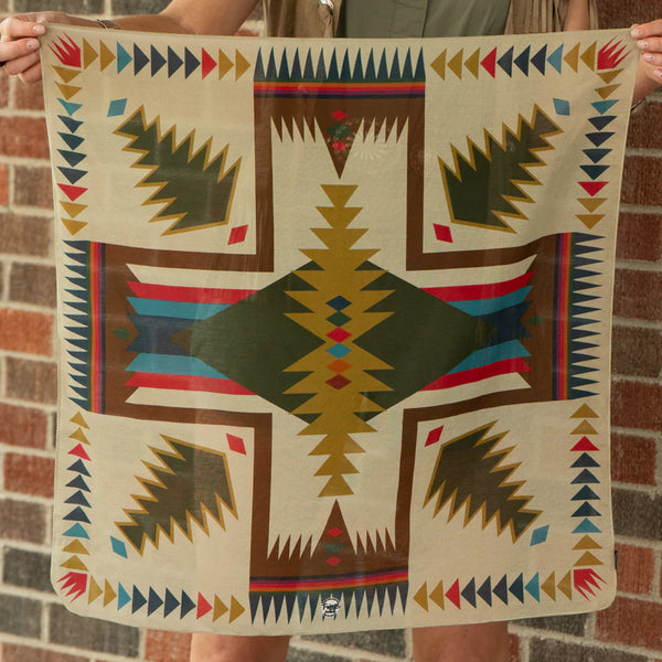 Person holding a colorful patterned fabric against a brick wall