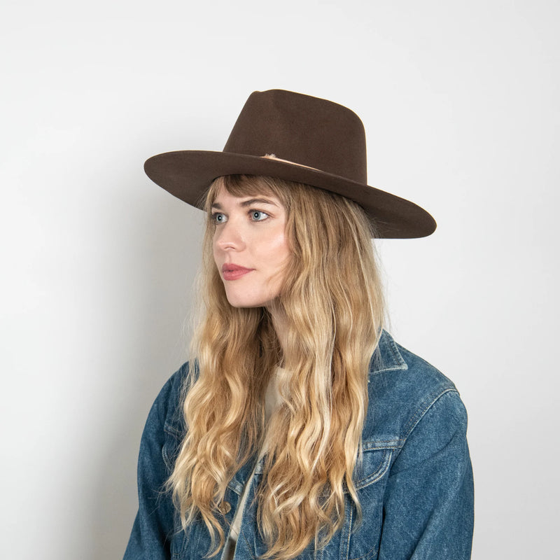 Woman wearing a brown hat and denim jacket against a white background