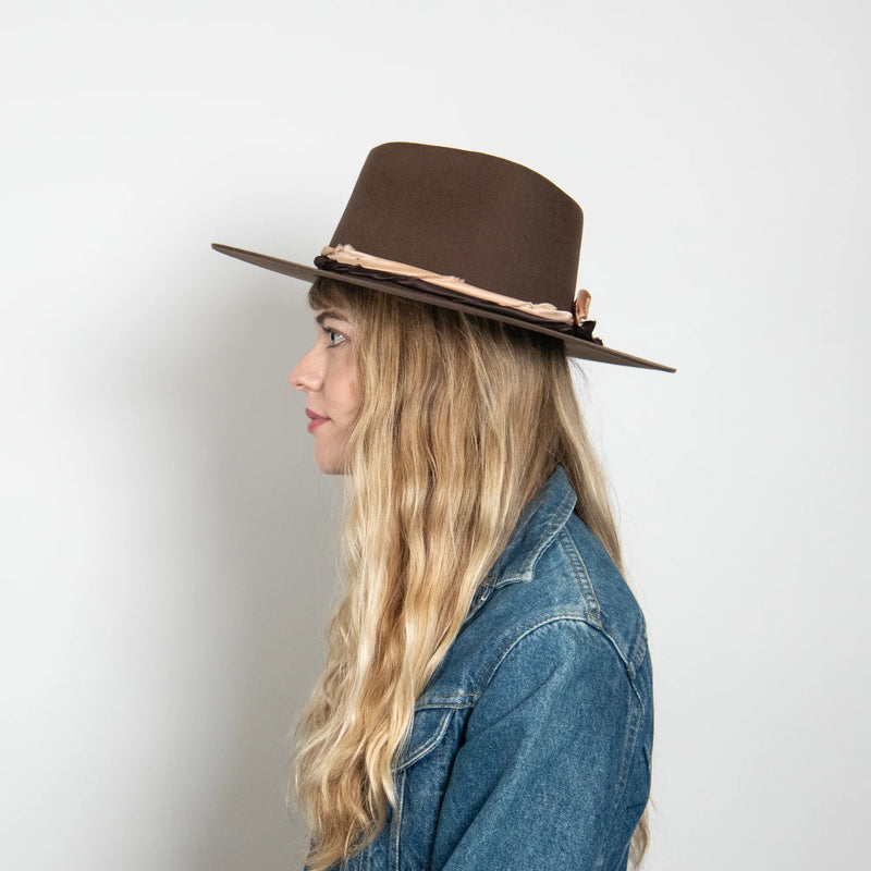 Woman wearing a brown hat and denim jacket on a white background