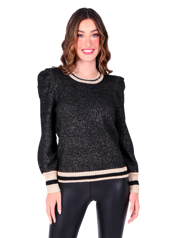 Woman wearing black sweater with metallic reflex in it with cream and black stripe embellishment on cuff, hem and neckline