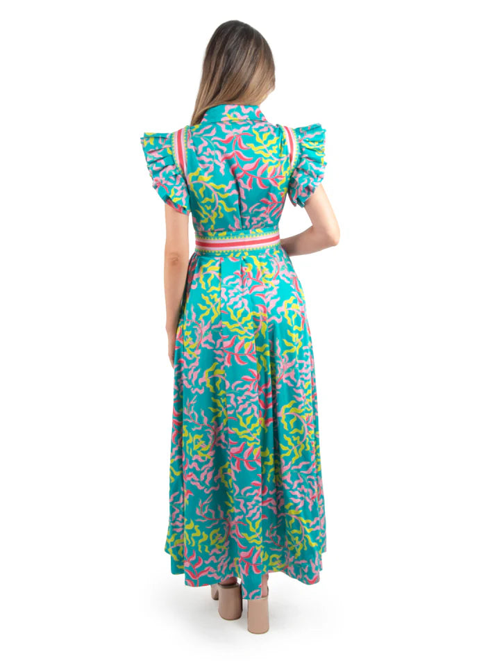 Woman wearing vibrant maxi dress with puff sleeves, green and pink leaf pattern and blue base with matching belt