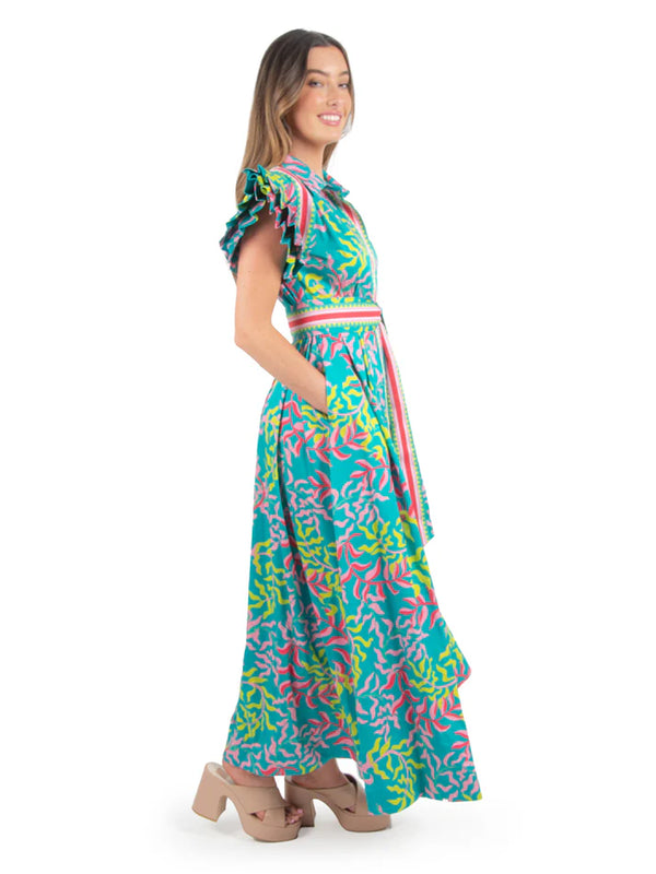 Woman wearing vibrant maxi dress with puff sleeves, green and pink leaf pattern and blue base with matching belt
