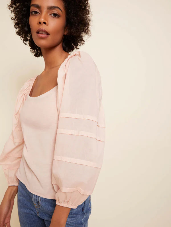 Woman wearing pink long sleeve top with texture on the balloon long sleeves