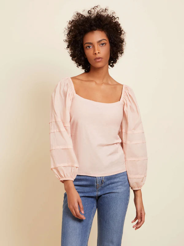 Woman wearing pink long sleeve top with texture on the balloon long sleeves