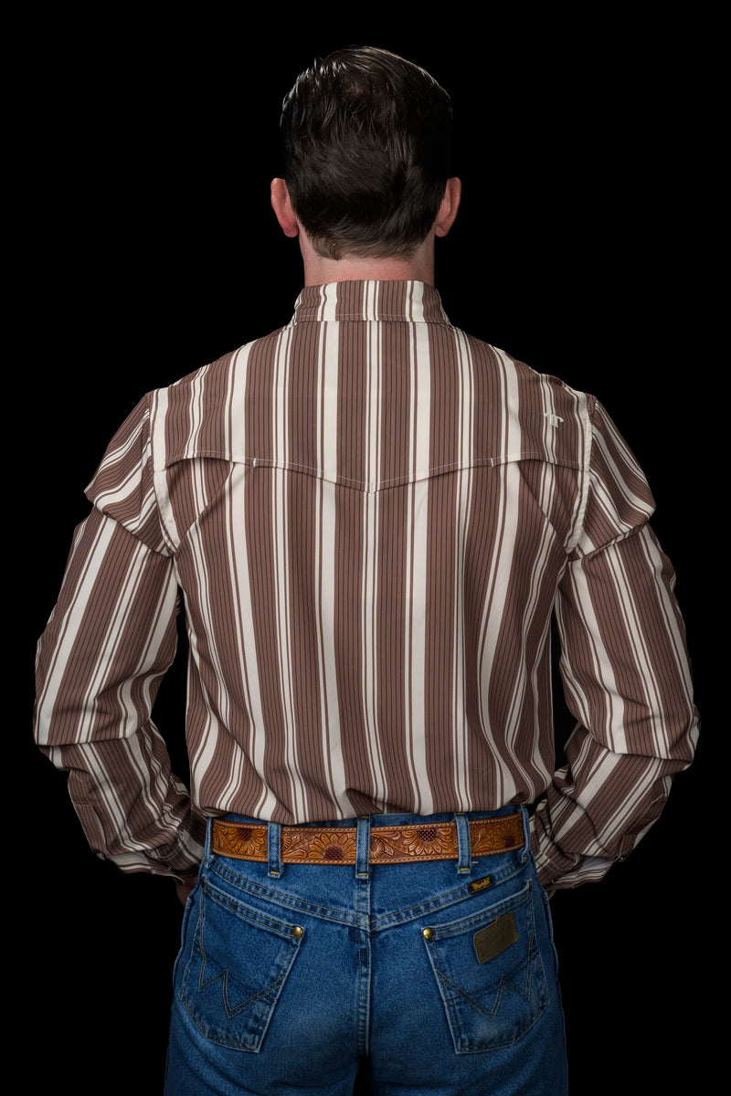 Man wearing a brown and white striped shirt with long sleeves and blue jeans on a black background