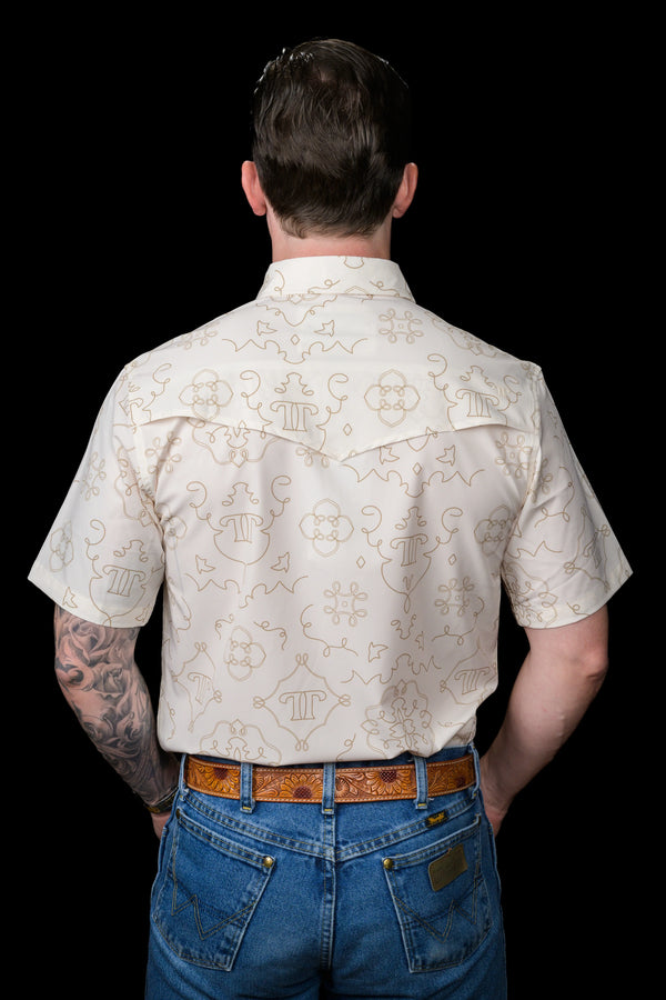 Man wearing a patterned shirt and jeans on a black background