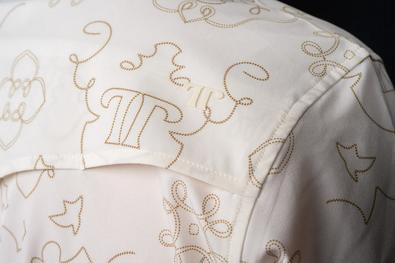Close-up of a white garment with gold embroidery on a dark background