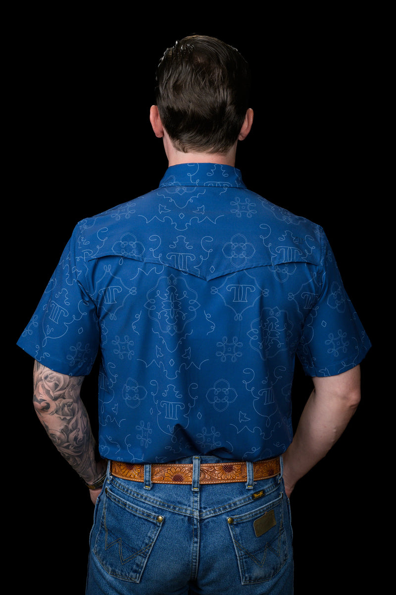 Person wearing a blue patterned shirt and jeans on a black background