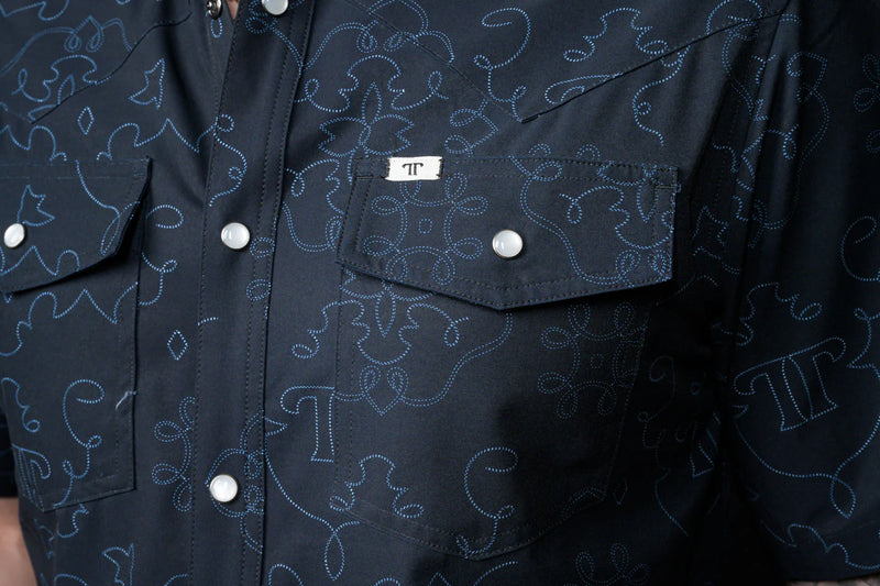 Navy blue shirt with white button details and a brand logo on a dark background