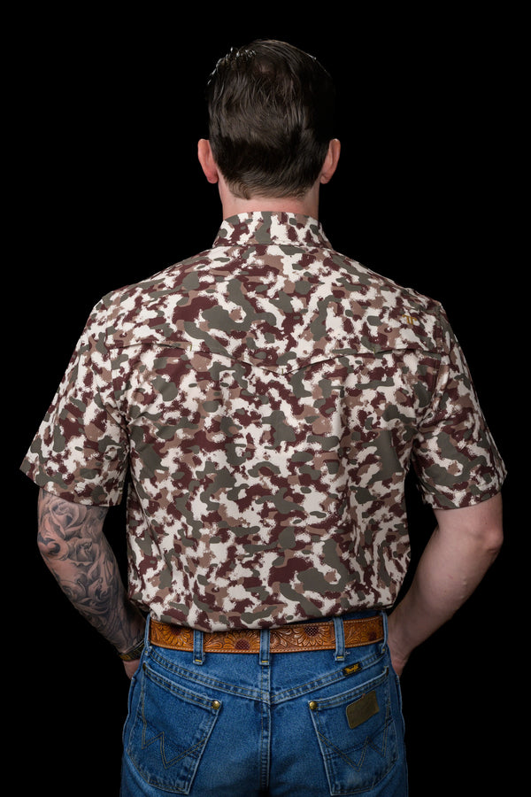 Man wearing a camouflage shirt and blue jeans on a black background