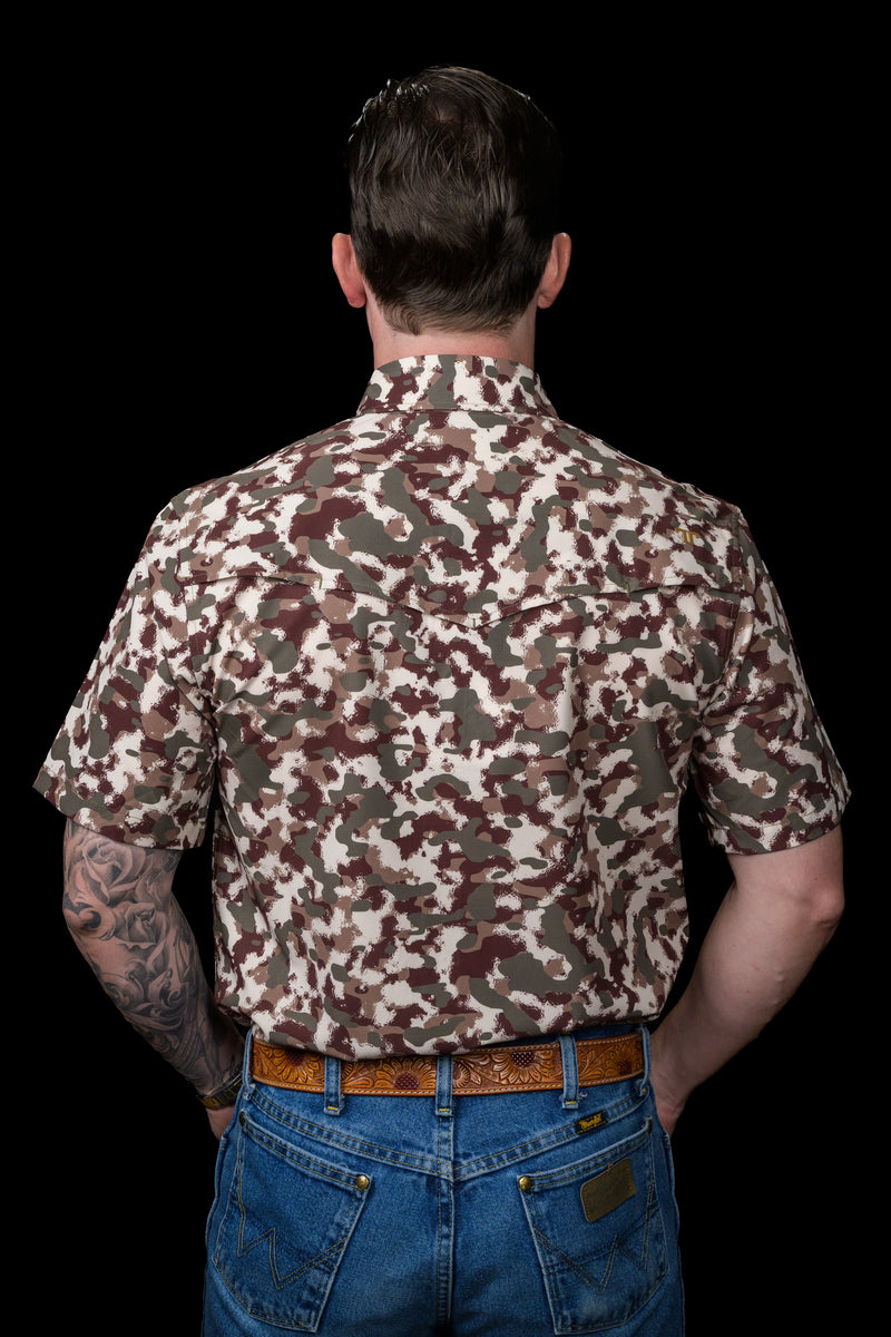 Man wearing a camouflage shirt and blue jeans on a black background