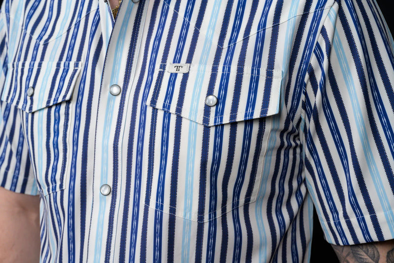Close-up of a person wearing a blue and white striped shirt with a brand logo.