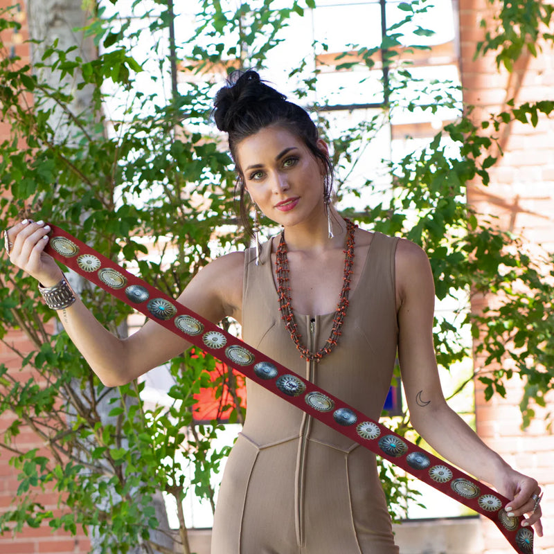 Woman holding a decorative belt with a plant and building in the background