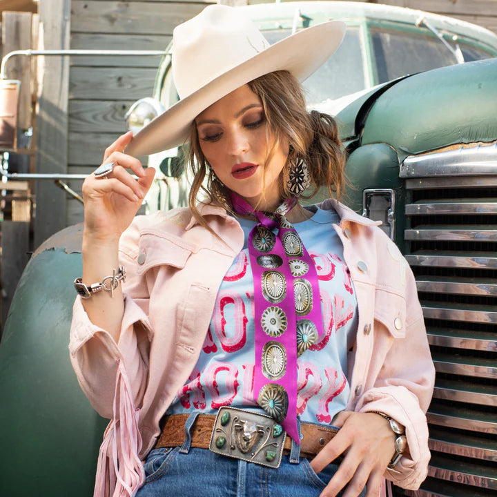 Woman in cowboy hat and pink jacket with a vintage car in the background