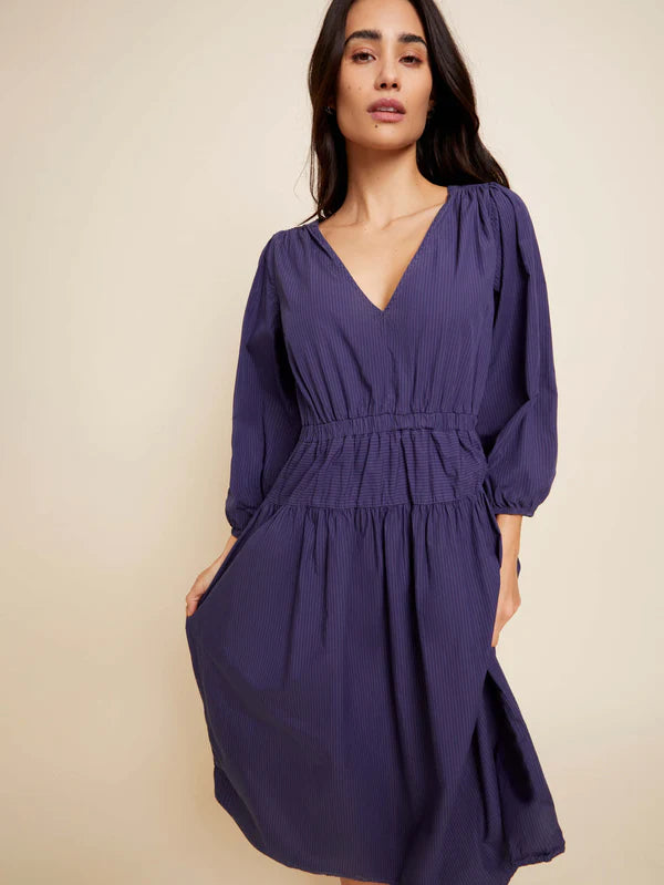 Woman wearing long sleeve dark purple dress with v neck and cinch waist with balloon sleeves
