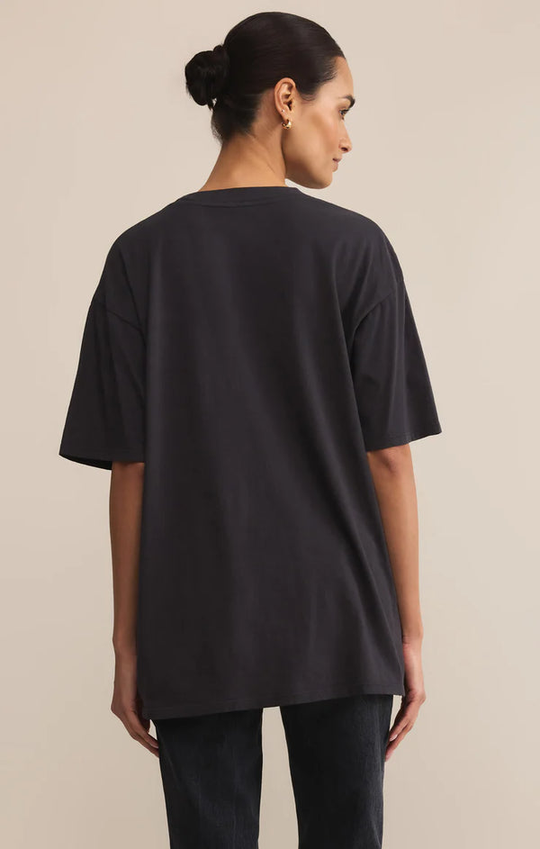 Woman wearing a black oversized t-shirt against a beige background