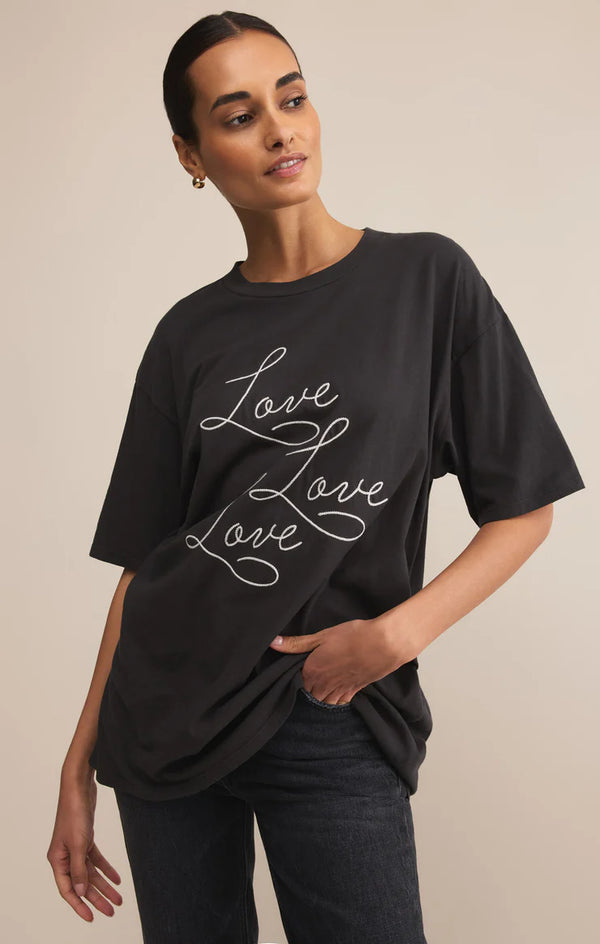 Woman wearing a black t-shirt with 'Love Love Love' text on a beige background