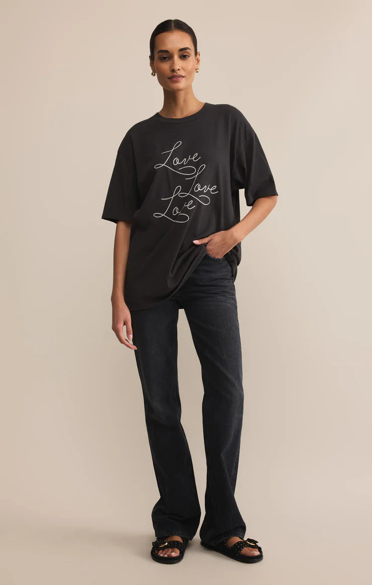 Person wearing a black t-shirt with 'Love' text on a beige background