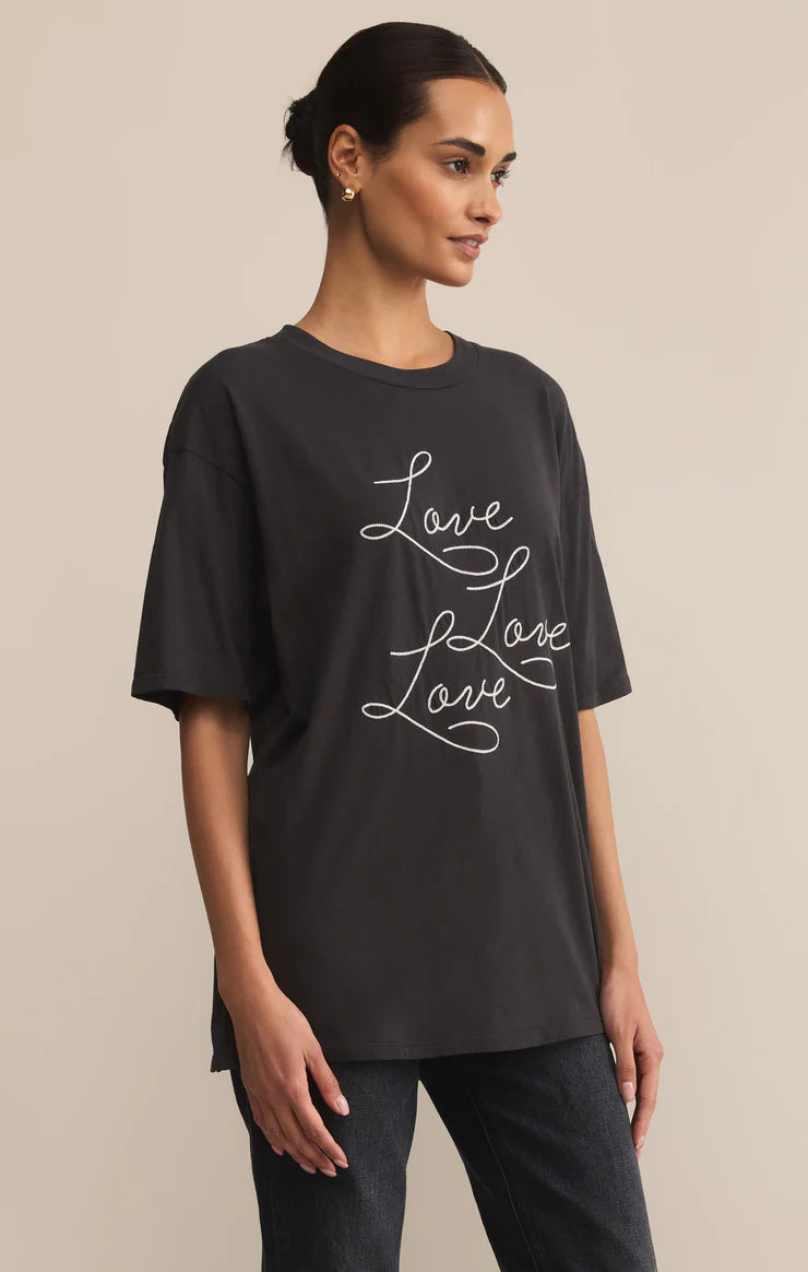 Woman wearing a black t-shirt with 'Love Love Love' text on a beige background