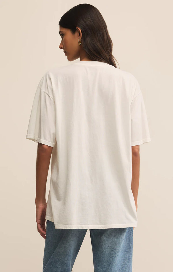 Woman wearing a white t-shirt and blue jeans against a beige background