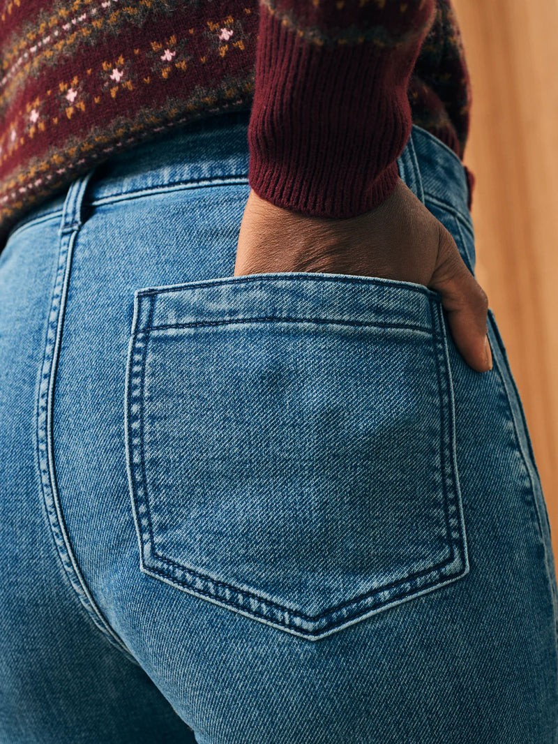 Woman wearing flair leg jeans in a medium blue color